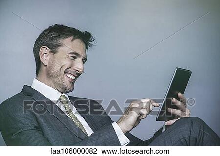Man laughing while using digital tablet View Large Photo Image Stock Image - Man laughing while using digital tablet. Fotosearch