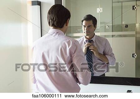 Man looking in bathroom mirror, adjusting necktie View Large Photo Image Stock Image - Man looking in bathroom mirror, adjusting necktie. Fotosearch