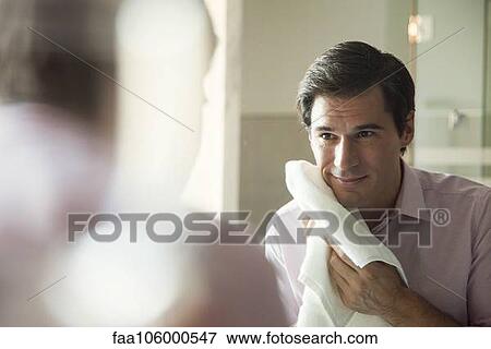 Man looking in mirror, drying his face with a towel View Large Photo Image Stock Photo - Man looking in mirror, drying his face with a towel. Fotosearch