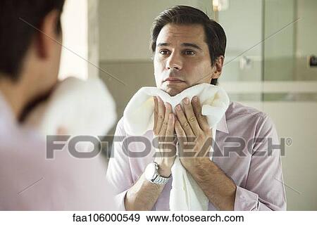 Man looking in mirror, drying his face with a towel View Large Photo Image Stock Photo - Man looking in mirror, drying his face with a towel. Fotosearch