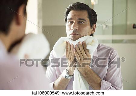 Man looking in mirror, drying his face with a towel View Large Photo Image Stock Photo - Man looking in mirror, drying his face with a towel. Fotosearch