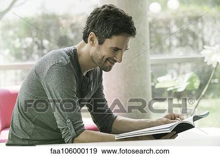 Stock Photo - Man looking through magazine while waiting in waiting room. Fotosearch