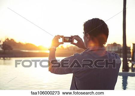 Man photographing sunset with smartphone View Large Photo Image Stock Image - Man photographing sunset with smartphone. Fotosearch