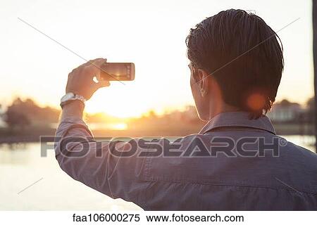 Man photographing sunset with smartphone View Large Photo Image Stock Photography - Man photographing sunset with smartphone. Fotosearch