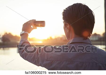 Man photographing sunset with smartphone View Large Photo Image Stock Photography - Man photographing sunset with smartphone. Fotosearch