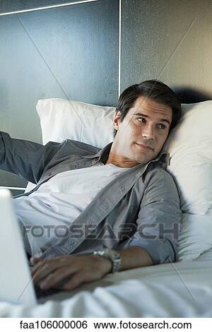 Man relaxing in bed with laptop computer View Large Photo Image Stock Photograph - Man relaxing in bed with laptop computer. Fotosearch