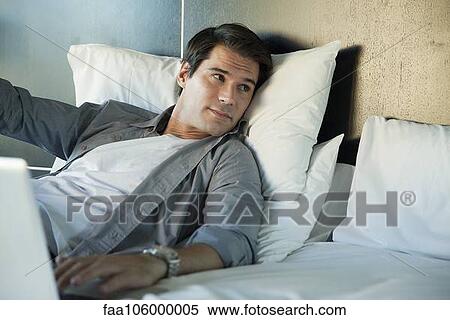 Man relaxing in bed with laptop computer View Large Photo Image Stock Photography - Man relaxing in bed with laptop computer. Fotosearch