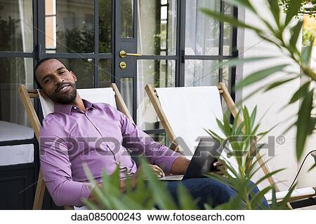 Man relaxing in deckchair View Large Photo Image Stock Image - Man relaxing in deckchair. Fotosearch