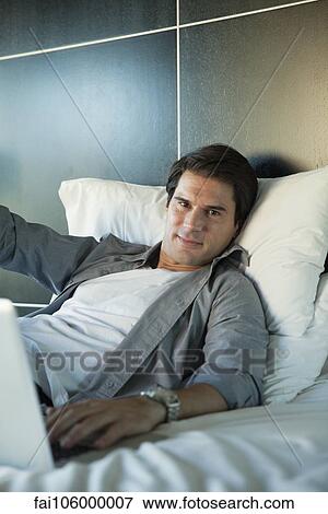 Stock Photo - Man relaxing on bed, portrait. Fotosearch