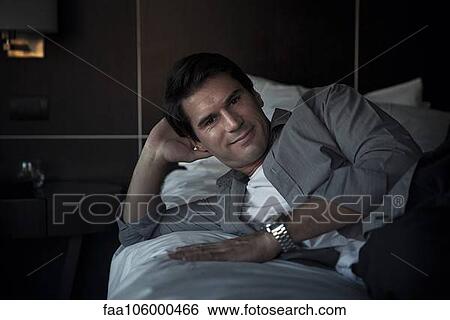 Man relaxing on bed, portrait View Large Photo Image Stock Photograph - Man relaxing on bed, portrait. Fotosearch