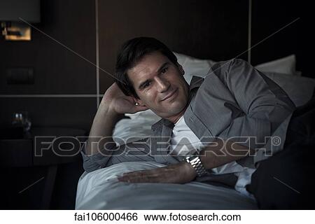 Man relaxing on bed, portrait View Large Photo Image Stock Photograph - Man relaxing on bed, portrait. Fotosearch
