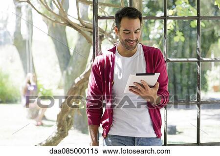 Man relaxing with digital tablet View Large Photo Image Stock Photography - Man relaxing with digital tablet. Fotosearch