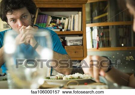 Man sitting at dinner table with hands clasped in front of his mouth View Large Photo Image Stock Photo - Man sitting at dinner table with hands clasped in front of his mouth. Fotosearch