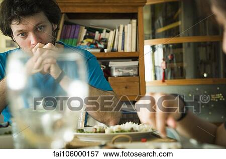 Man sitting at dinner table with hands clasped in front of his mouth View Large Photo Image Stock Photo - Man sitting at dinner table with hands clasped in front of his mouth. Fotosearch
