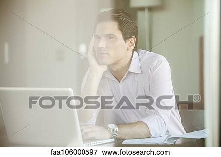 Man sitting before laptop computer, daydreaming in office View Large Photo Image Stock Photo - Man sitting before laptop computer, daydreaming in office. Fotosearch