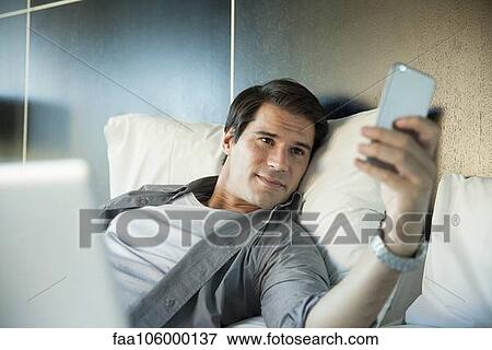Man smiling at multimedia smartphone View Large Photo Image Stock Photo - Man smiling at multimedia smartphone. Fotosearch
