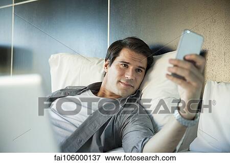 Man smiling at multimedia smartphone View Large Photo Image Stock Photo - Man smiling at multimedia smartphone. Fotosearch