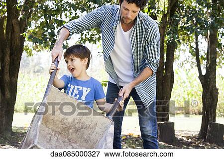Man teaching young son how to use wheelbarrow View Large Photo Image Stock Photo - Man teaching young son how to use wheelbarrow. Fotosearch