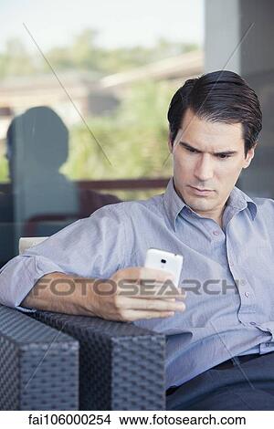 Picture - Man text messaging with smartphone. Fotosearch