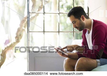 Man using digital tablet at home View Large Photo Image Picture - Man using digital tablet at home. Fotosearch