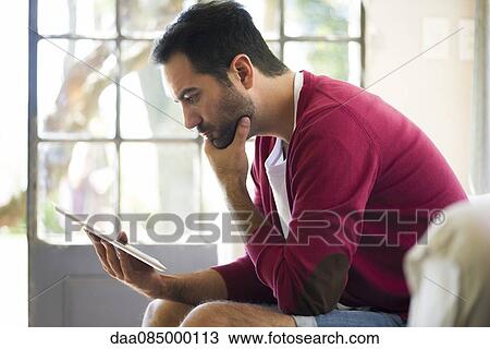 Man using digital tablet at home View Large Photo Image Stock Image - Man using digital tablet at home. Fotosearch