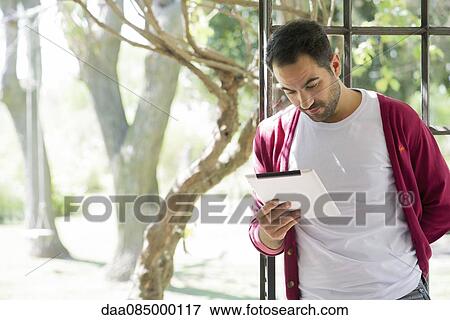 Man using digital tablet at home View Large Photo Image Stock Photo - Man using digital tablet at home. Fotosearch