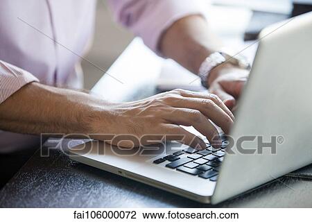 Stock Image - Man using laptop computer, cropped. Fotosearch