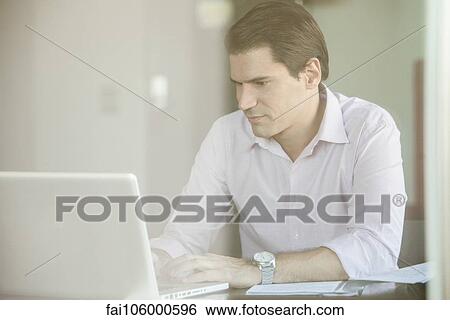 Man using laptop computer in office View Large Photo Image Stock Photograph - Man using laptop computer in office. Fotosearch
