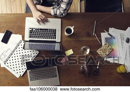 Man using laptop computer on desk cluttered with documents View Large Photo Image Stock Photo - Man using laptop computer on desk cluttered with documents. Fotosearch
