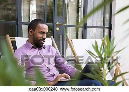 Stock Image - Man using laptop computer outdoors. Fotosearch