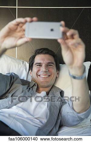 Stock Image - Man using smartphone to take a selfie. Fotosearch
