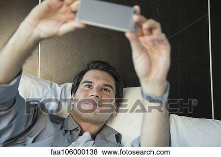 Man using smartphone to take a selfie View Large Photo Image Stock Photo - Man using smartphone to take a selfie. Fotosearch