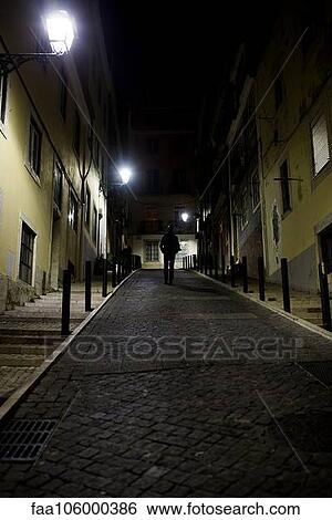 Man walking on cobblestone street at night View Large Photo Image Stock Photograph - Man walking on cobblestone street at night. Fotosearch