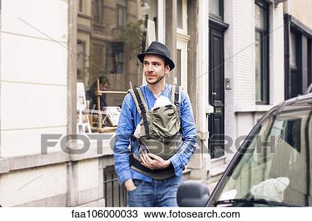 Man with baby in carrier on the move in the city View Large Photo Image Stock Image - Man with baby in carrier on the move in the city. Fotosearch