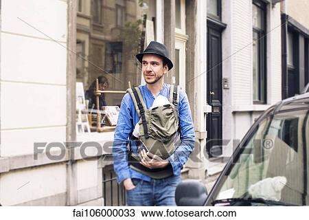 Man with baby in carrier on the move in the city View Large Photo Image Stock Image - Man with baby in carrier on the move in the city. Fotosearch