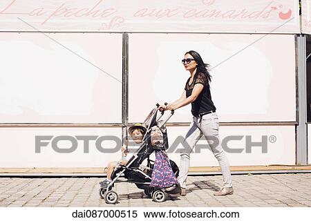 Mother pushing toddler son in stroller on sidewalk View Large Photo Image Stock Photography - Mother pushing toddler son in stroller on sidewalk. Fotosearch
