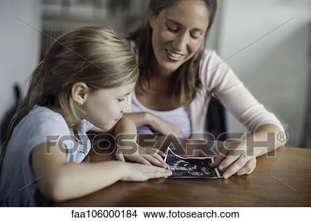Mother showing daughter ultrasound photo View Large Photo Image Picture - Mother showing daughter ultrasound photo. Fotosearch