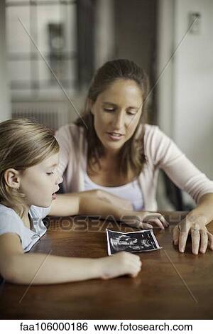 Mother showing daughter ultrasound photo View Large Photo Image Stock Photograph - Mother showing daughter ultrasound photo. Fotosearch