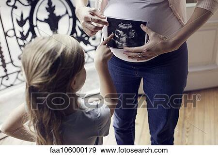 Mother using ultrasound photo to prepare daughter for imminent arrival of new sibling View Large Photo Image Stock Photo - Mother using ultrasound photo to prepare daughter for imminent arrival of new sibling. Fotosearch
