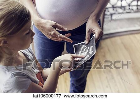 Mother using ultrasound photo to prepare daughter for imminent arrival of new sibling View Large Photo Image Stock Photo - Mother using ultrasound photo to prepare daughter for imminent arrival of new sibling. Fotosearch