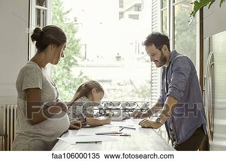 Stock Photography - Parents watching as daughter colors. Fotosearch