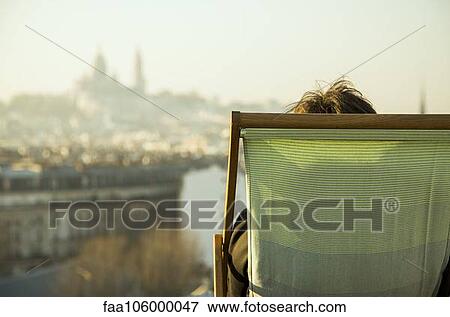 Person sitting in deckchair, looking at view of city View Large Photo Image Stock Photo - Person sitting in deckchair, looking at view of city. Fotosearch