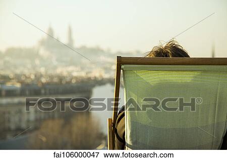 Person sitting in deckchair, looking at view of city View Large Photo Image Stock Photo - Person sitting in deckchair, looking at view of city. Fotosearch