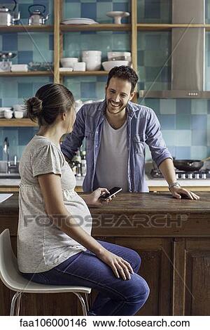 Pregnant wife chatting with husband in kitchen View Large Photo Image Stock Photograph - Pregnant wife chatting with husband in kitchen. Fotosearch