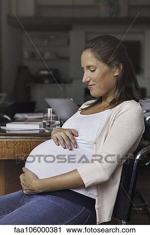 Pregnant woman cradling belly, portrait View Large Photo Image Stock Image - Pregnant woman cradling belly, portrait. Fotosearch