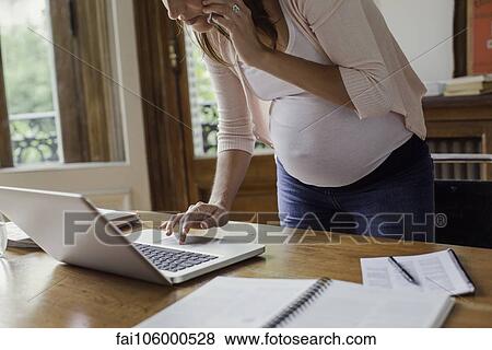 Pregnant woman using laptop computer and making phone call View Large Photo Image Stock Photo - Pregnant woman using laptop computer and making phone call. Fotosearch