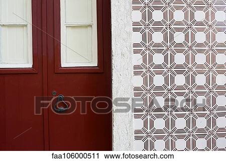 Stock Image - Red door and ornate tiled wall. Fotosearch