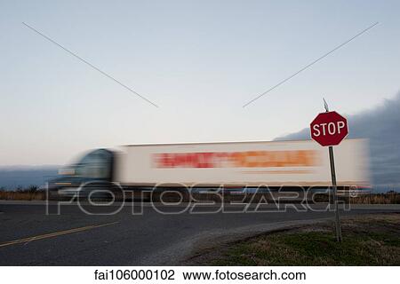 Semi truck moving on road near stop sign View Large Photo Image Stock Image - Semi truck moving on road near stop sign. Fotosearch
