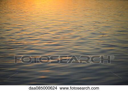 Sunset reflected on surface of water View Large Photo Image Picture - Sunset reflected on surface of water. Fotosearch