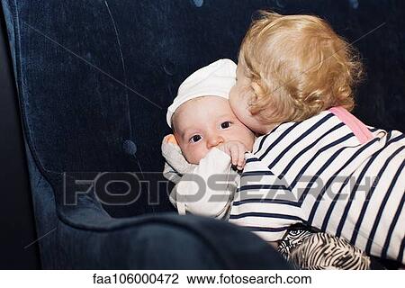 Stock Image - Toddler embracing infant sibling. Fotosearch